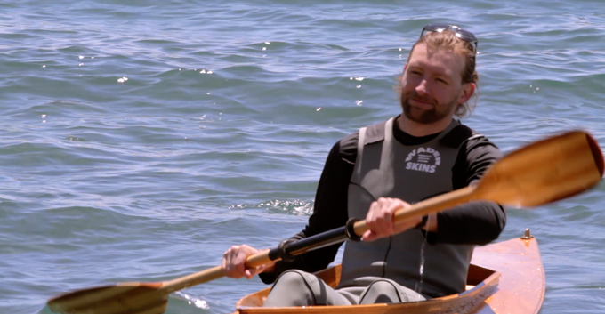 kayaker wearing wader skins paddling in lake